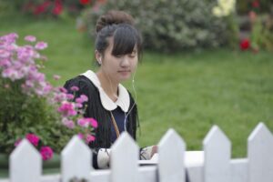 woman in black sitting in a garden listening to gardening podcasts