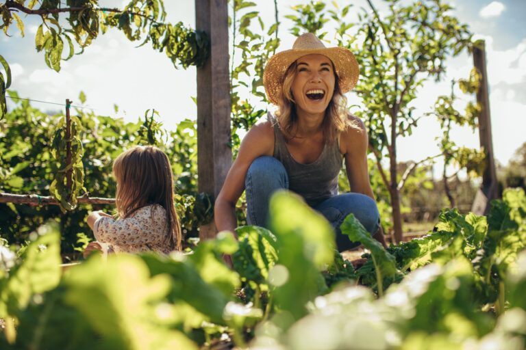 happy woman in garden wearing a straw hat, gardening and self care health benefits of gardening