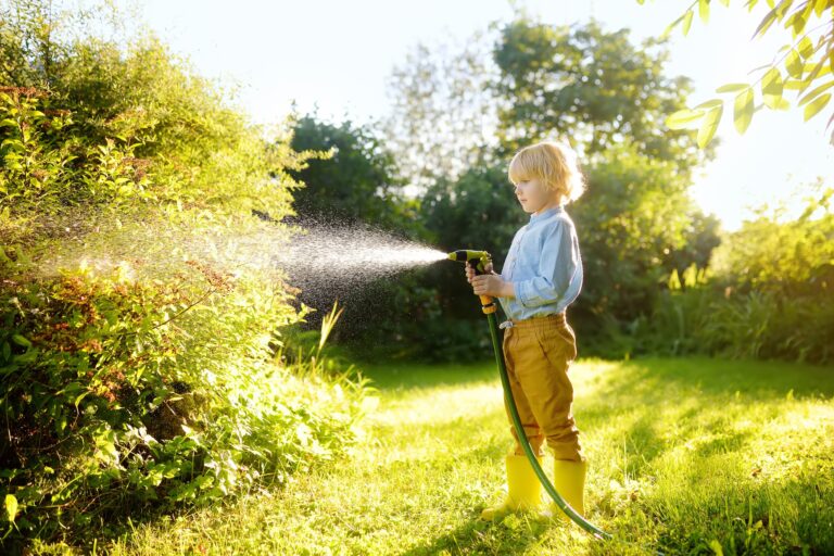 little boy watering a garden featured image for reduce water usage in the garden
