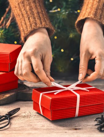 gifts for gardeners: female hands wrapping a red christmas present