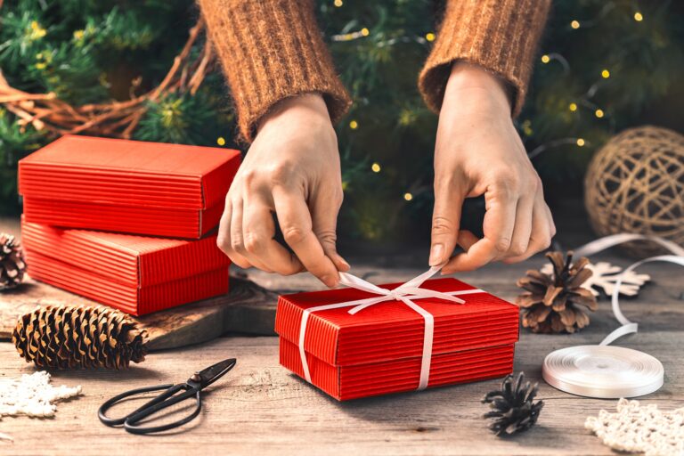 gifts for gardeners: female hands wrapping a red christmas present