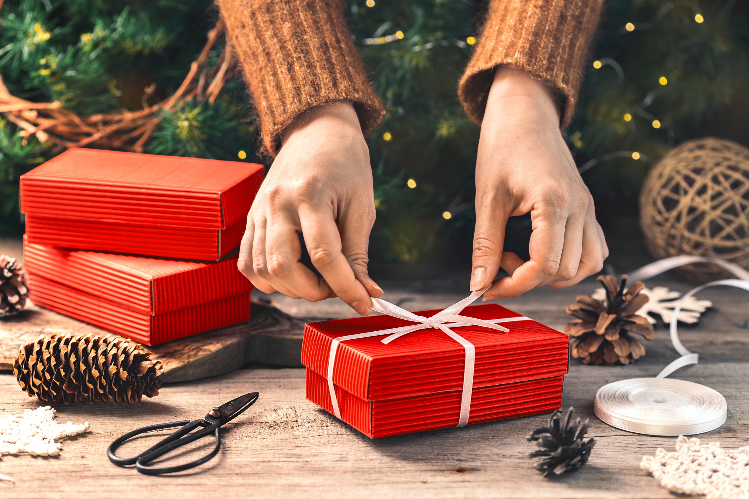 gifts for gardeners: female hands wrapping a red christmas present